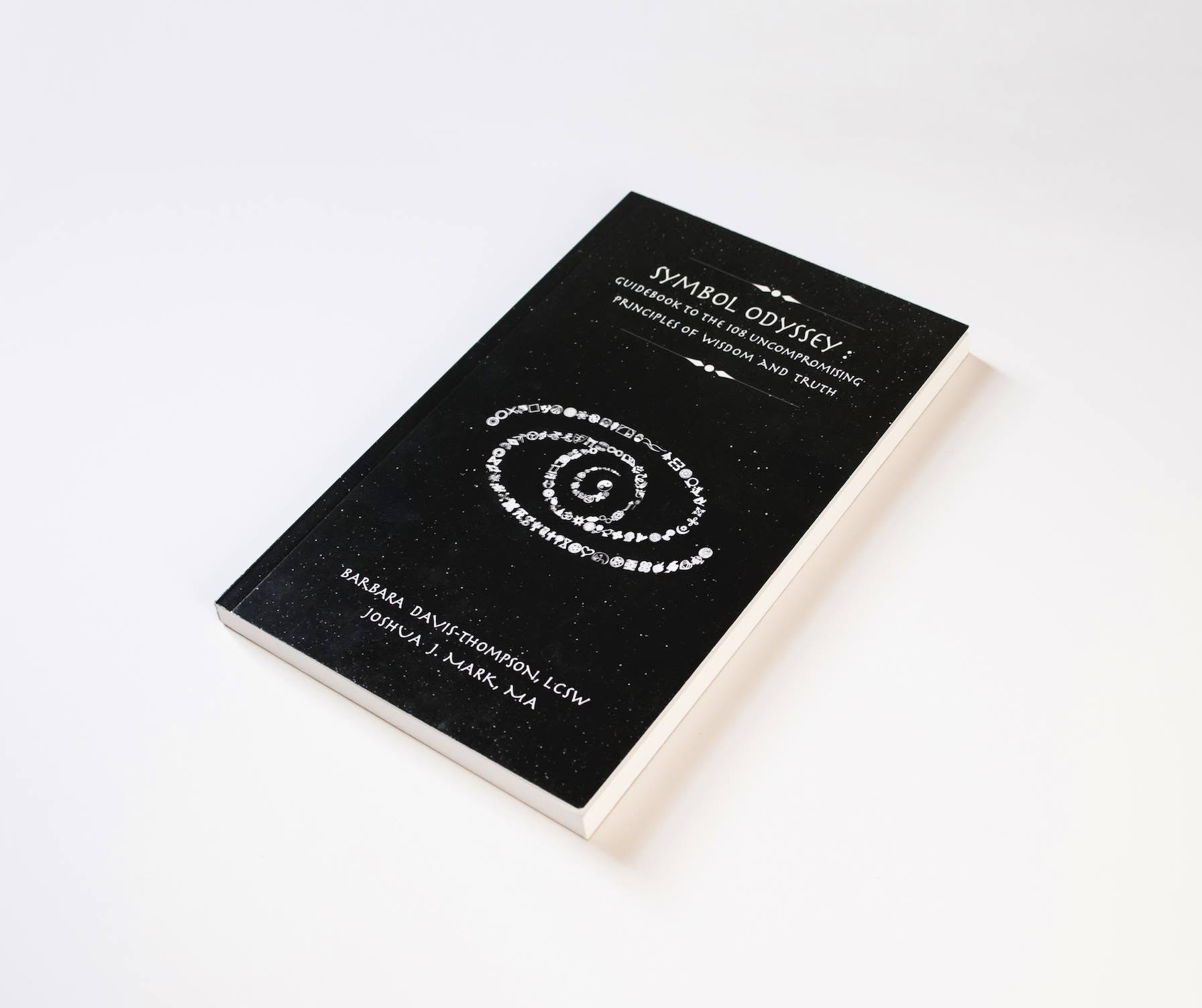 The physical black Symbol Odyssey book photographed at an angle on a white background