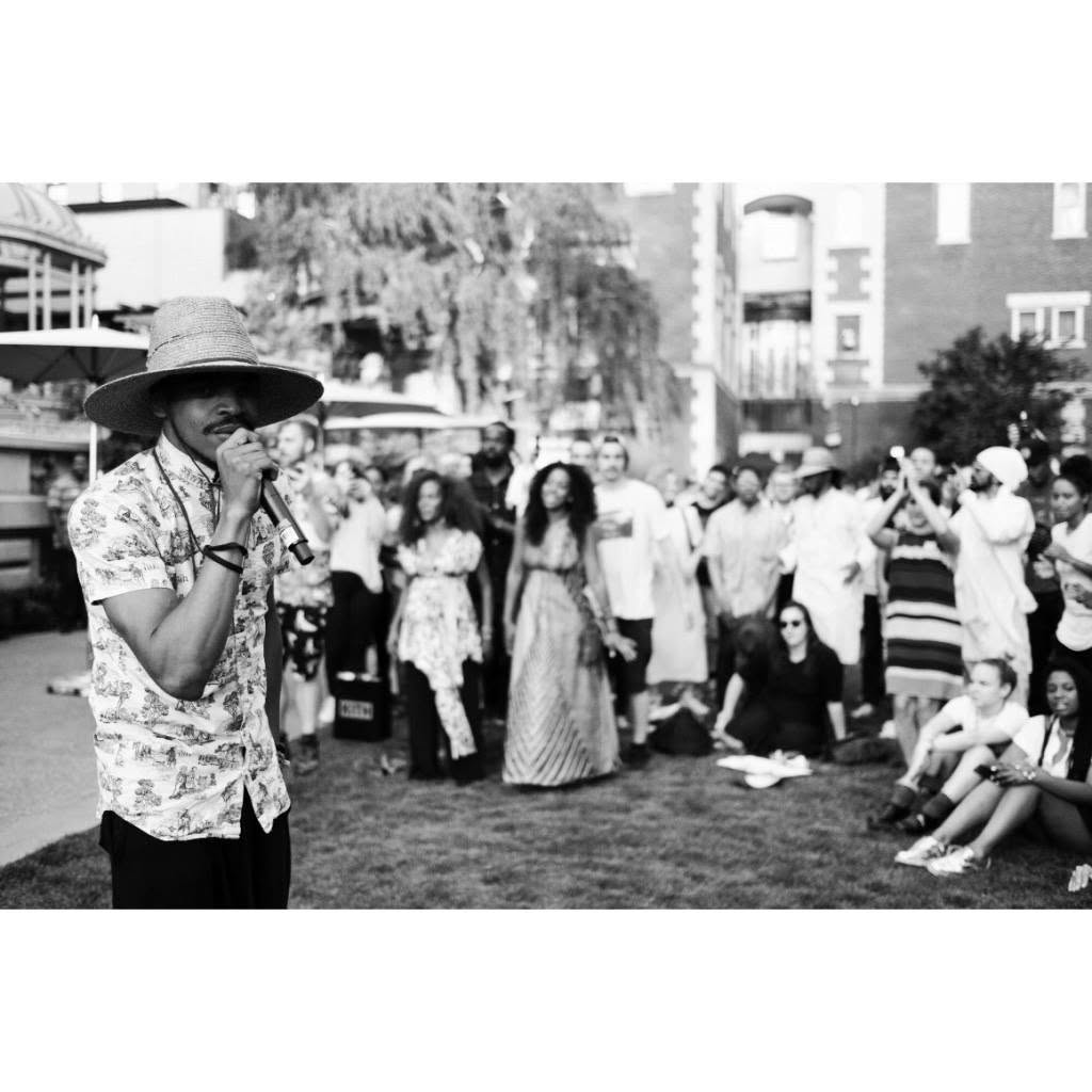 KAMAUU performing into a microphone before a garden audience at Cooper Hewitt, black and white
