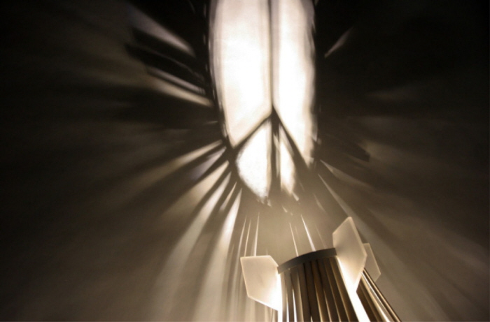 Peacebomb casting radiating light and shadow onto a wall
