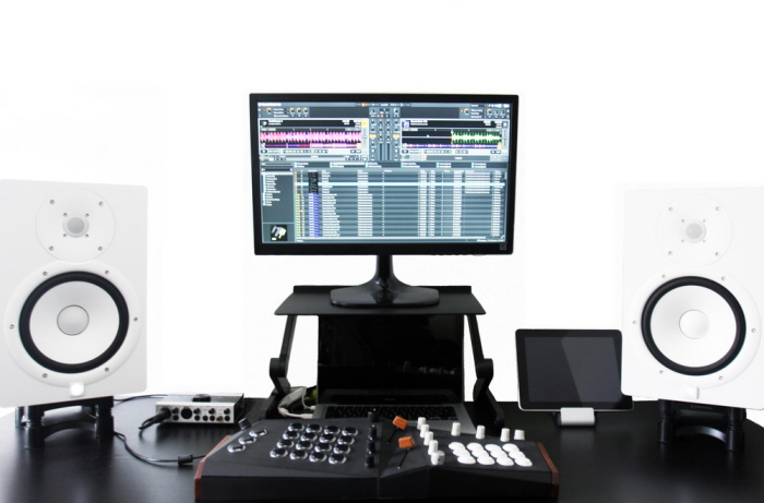 Lucid positioned at a music workstation between two studio speakers