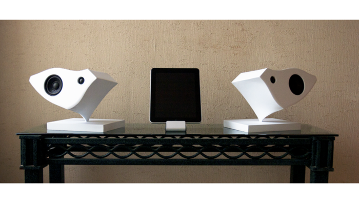A pair of white Kardia speakers arranged on either side of a small music player