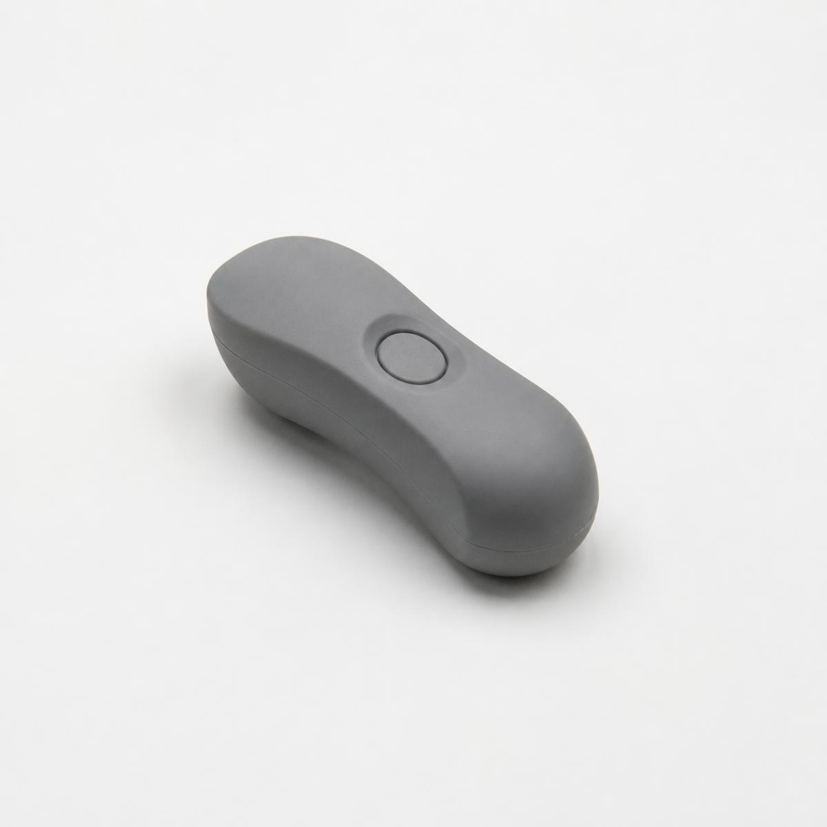 A small grey handheld object with a single recessed button
