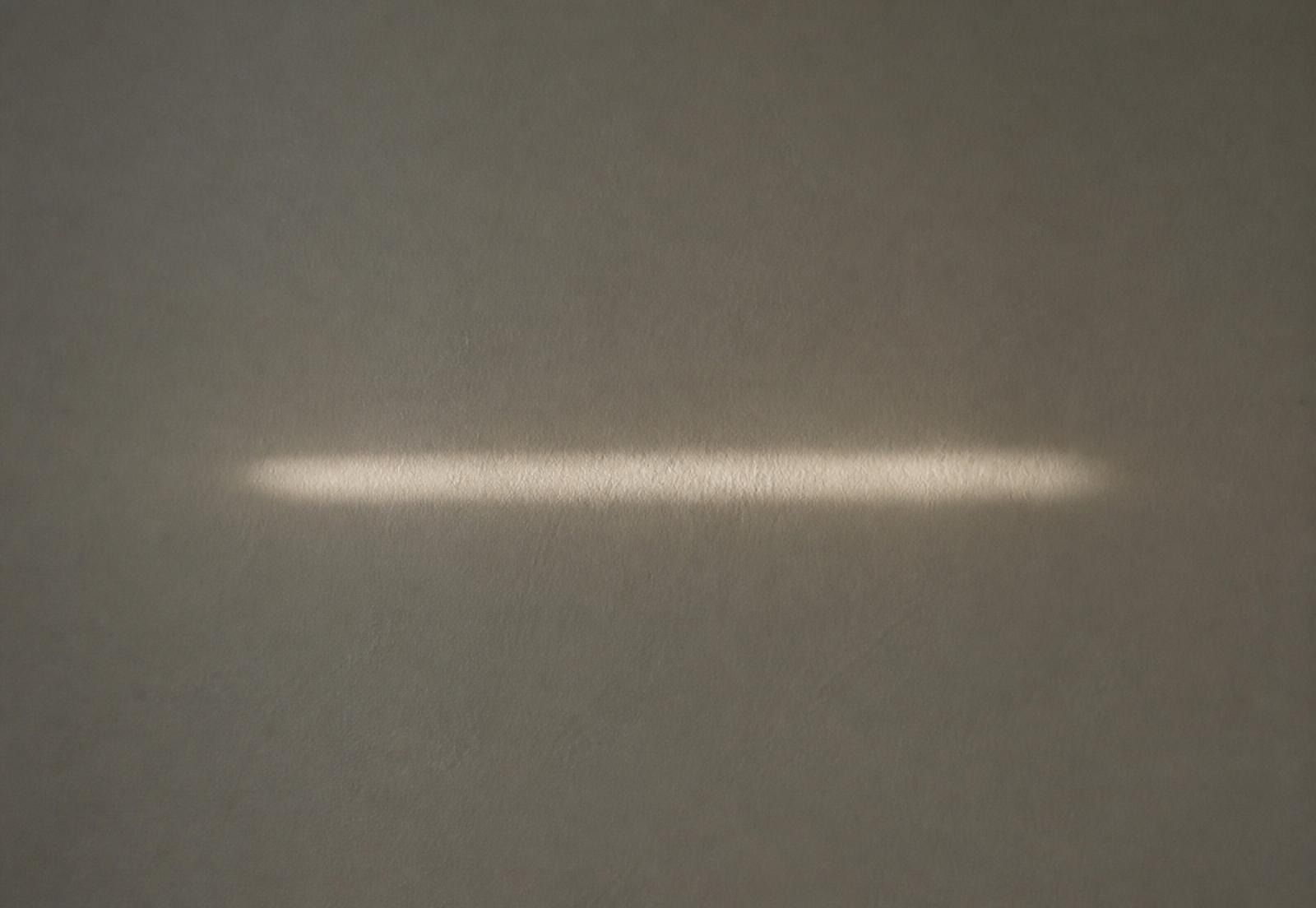 A thin line of light falling across a plain wall